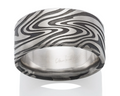 A wide silver band ring featuring a black and silver wavy damascus pattern on the exterior, with a polished silver interior. 