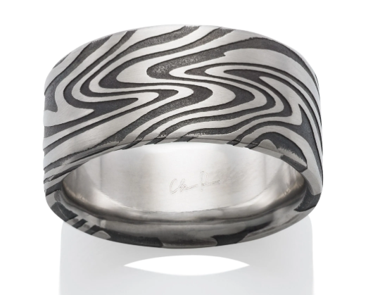 A wide silver band ring featuring a black and silver wavy damascus pattern on the exterior, with a polished silver interior. 