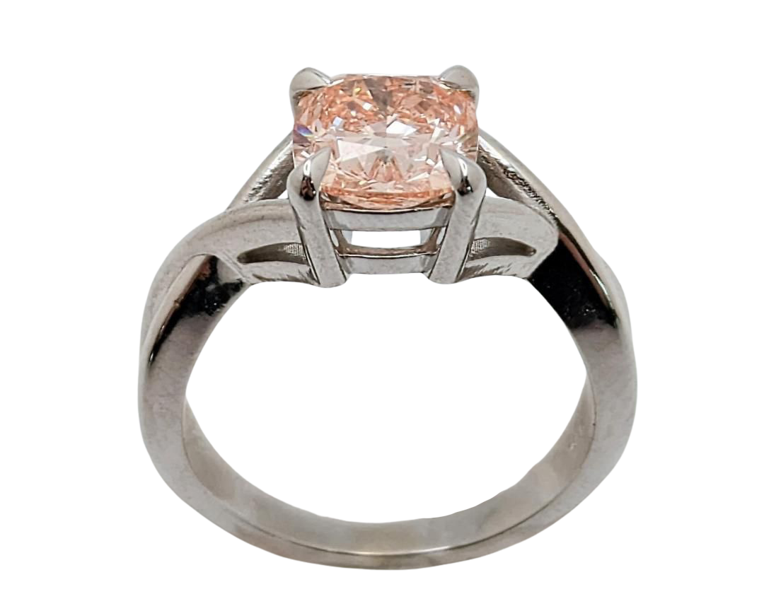 A pink diamond ring with a cushion-cut center stone, set in claw prongs in a silver-toned twisted shank, isolated on a white background.