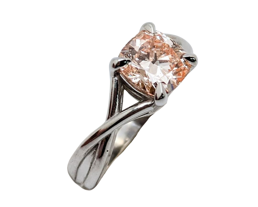 A pink cushion-cut diamond ring with a silver-toned twisted band, shown from the side and isolated on a white background.