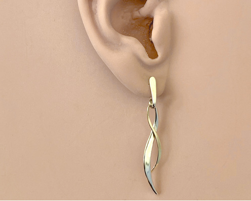 A pair of modern twisted drop earrings with a dual-tone finish, featuring one gold-toned and one silver-toned twisted ribbon design with flat post ends, shown on a ear model.
